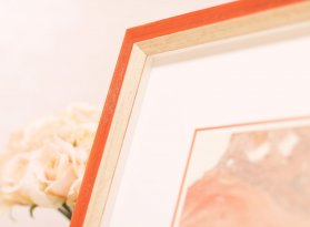 Prohloubený oranžový rám s patinou použitý na rámování PF 1983 od Jiřího Anderleho doplněný bílou paspartou s oranžovým řezem – pohled na levý horní roh rámu.