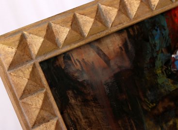 Detailní pohled na vyřezávaný geometrický vzor modelového rámu k obrazu Martina Velíška Satyr velikonoce. Dekor tvaru pravidelných opakujících se pyramid je vyzlacený plátkovým kovem má výraznou kartáčovnou patinu.