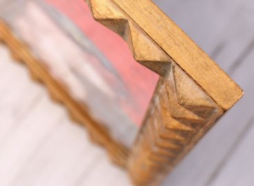 Detailní pohled na bok luxusního na zakázku vyrobeného obrazového rámu s profilem geometrických pyramid vyzlacených plátkovým kovem s kartáčováním a patinou stáří. 