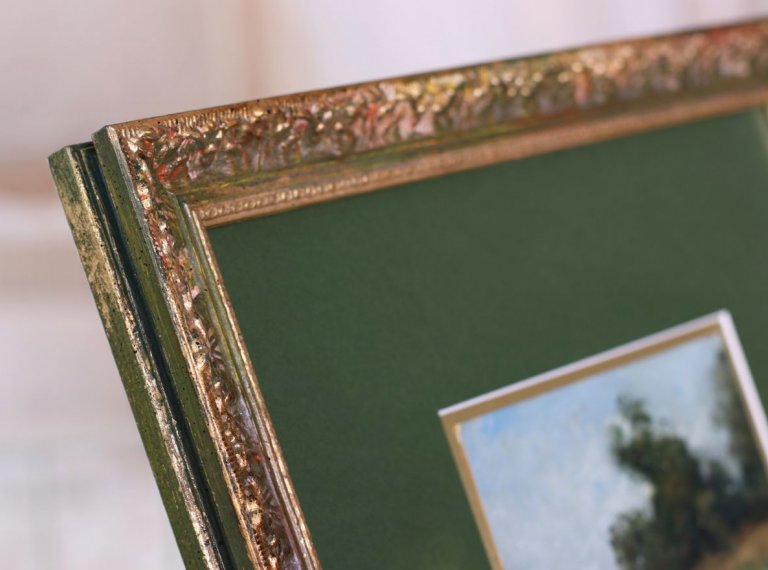 Roh zeleného ornamentálního rámu spolu se zelenou a zlatou paspartou použitých a obraze krajiny na kartonu