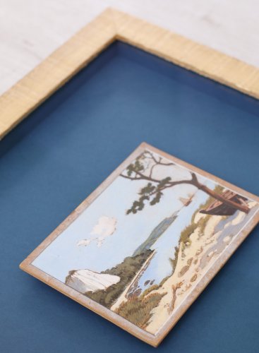 Po zarámování se malý obraz zátoky ve zlatém rámu jakoby sám vznáší nad modrým podkladem