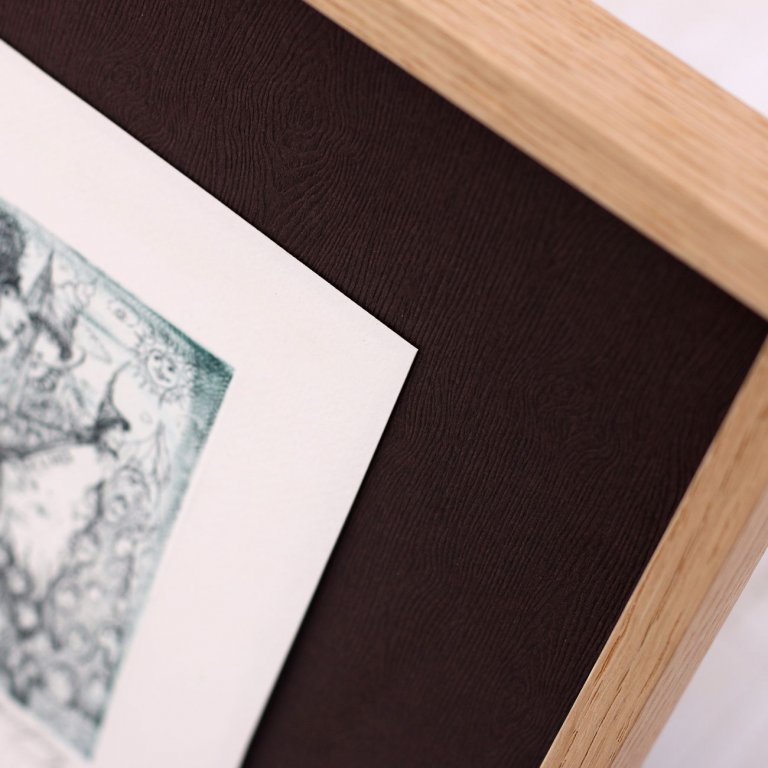 Detail dřevěné struktury tmavohnědé zakázkové pasparty s moderním minimalistickým dubovým rámem a malým grafickým listem. 