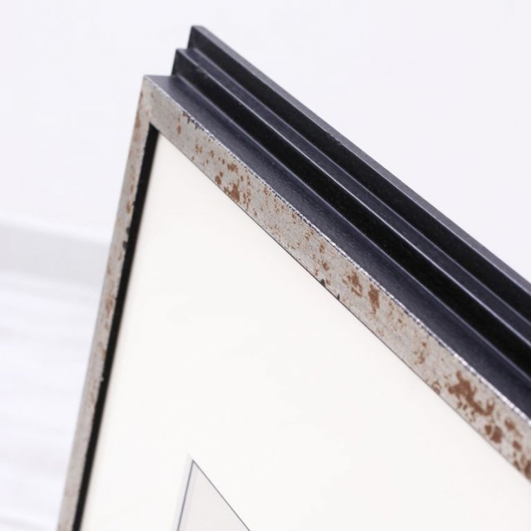 Detailní pohled na dřevěný rám se stříbrnou linkou a věrnou patinou evokující věkovitost a dvojici paspart.