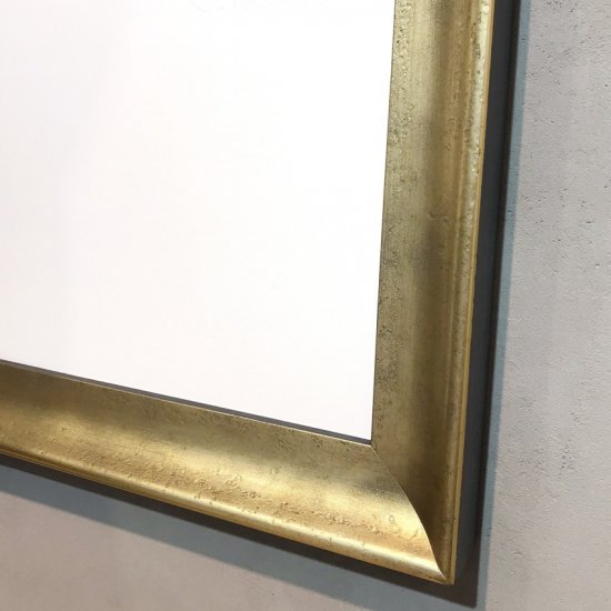 Metalický rám na reprodukci Salvadora Dalí ve zlatém provedení s nepravidelným povrchem a černým vnějším bokem.