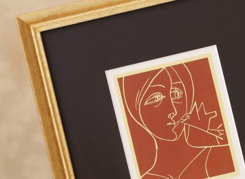 Linoryt Oty Janečka Dívka s ptáčkem s čokoládově hnědou paspartou a úzkým zlaceným rámem.