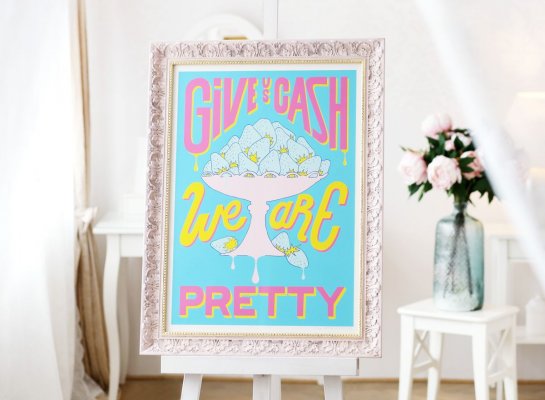 Rámování serigrafie Pasty Onera Give us Cash bez paspartování do luxusního růžového rámu s patinou a zlatou filetou s uzavřeným rohy umístěný na malířském stojanu v luxusním obývacím pokoji s kyticí v pozadí.