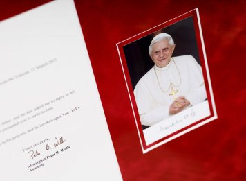 Fotografie papeže Benedikta je rámovaná ve dvojici sametových červených paspart 