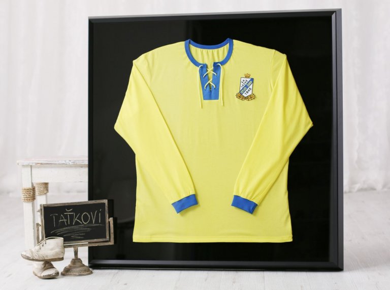 Historický žlutý fotbalový dres FK Teplice rámovaný do černého rámu a sametové pasparty 