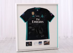 Fotbalový dres Marcello z Real Madrid je zarámovaný v bílém hlubokém rámu a na bílém podkladě. Boky rámu jsou tyrkysové, stejně jako barvy na tričku a rám je doplněný o vstupenku a fotografie ze zápasu