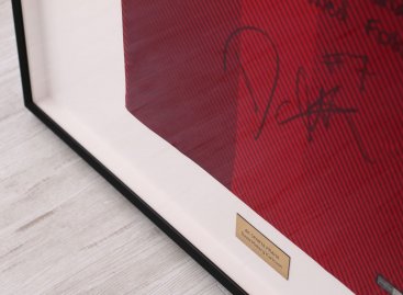 Moderní hluboký černý rám s bílým podkladem na rudé fotbalové tričko AC Sparta Praha Carlsson v detailním pohledu včetně části dresu s podpisem hráče a cedulkou.