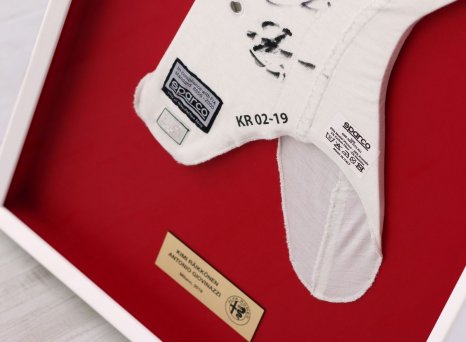 Prostorově rámovaná závodní kukla Formule 1 v bílém rámu na červené paspartě s gravírovanou cedulkou