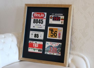 Běžecká startovní čísla v přírodním borovicovém rámu na tmavé paspartě