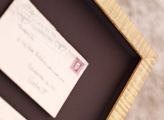 Zarámovaný historický dopis na tmavohnědém podkladě s prostorovým 3D efektem