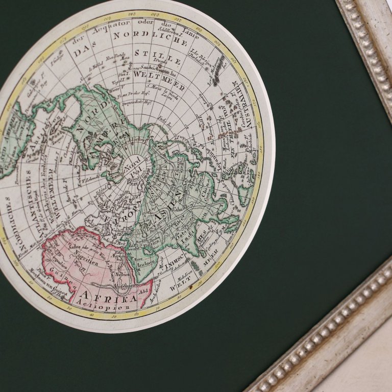 Tmavozelená muzeální pasparta s kruhovým výřezem s mapou severní polokoule