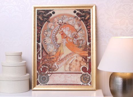 Křížková výšivka s motivem obrazu Alfonse Muchy napnutá v elegantním zlatém rámu