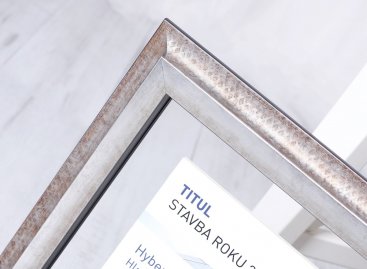 Diplom Stavba roku 2021 zarámovaný mezi dvě skla do industriálního rámu