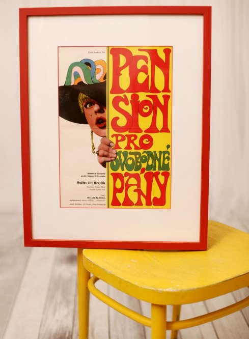 Filmový plakát Penzion pro svobodné pány v červeném rámu s bílou paspartou a červeným detailem ve výřezu