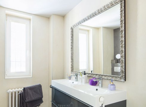 Elegantní koupelnové zrcadlo ve stříbrném ornamentálním rámu v moderní koupelně v Praze 6