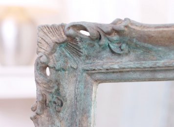 Oxidovaný etruský bronz na rohovém ornamentu luxusního blondelového rámu zrcadla