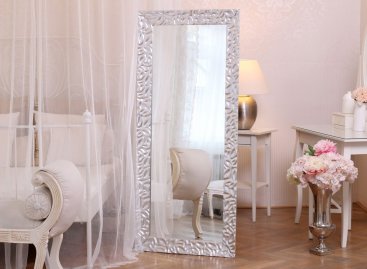 Vysoké stojící zrcadlo v moderním stříbrném rámu v interiéru luxusní ložnice