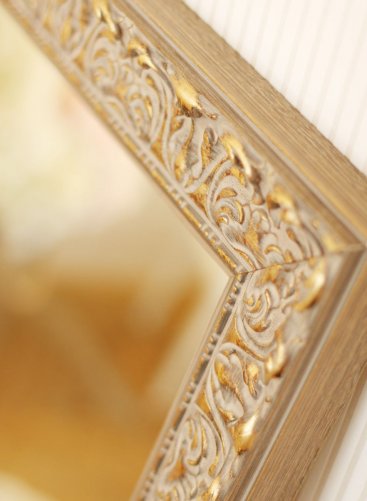 Detail zlatého bohatě ornamentálního rámu série Lira Larson-Juhl Praha s tradičně pojatým květinovým ornamentem a kvalitní hlubokou patinou s moderním zrcadlem.
