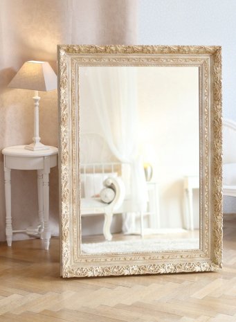 Krásné elegantní ornamentální zrcadlo v širokém stříbrném rámu v interiéru ložnice