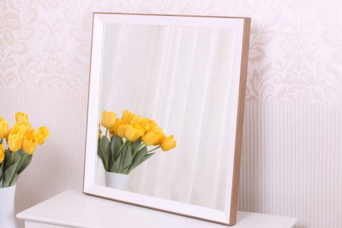 Moderní minimalistické čtvercové zrcadlo ve skandinávském stylu s rámem kombinujícím bílou a dřevo stojí v béžovém interiéru s vázou s tulipány.