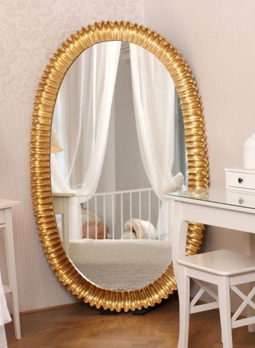 Luxusní oválné zrcadlo ve zlaceném moderně vyřezávaném rámu na zakázku v interiéru ložnice