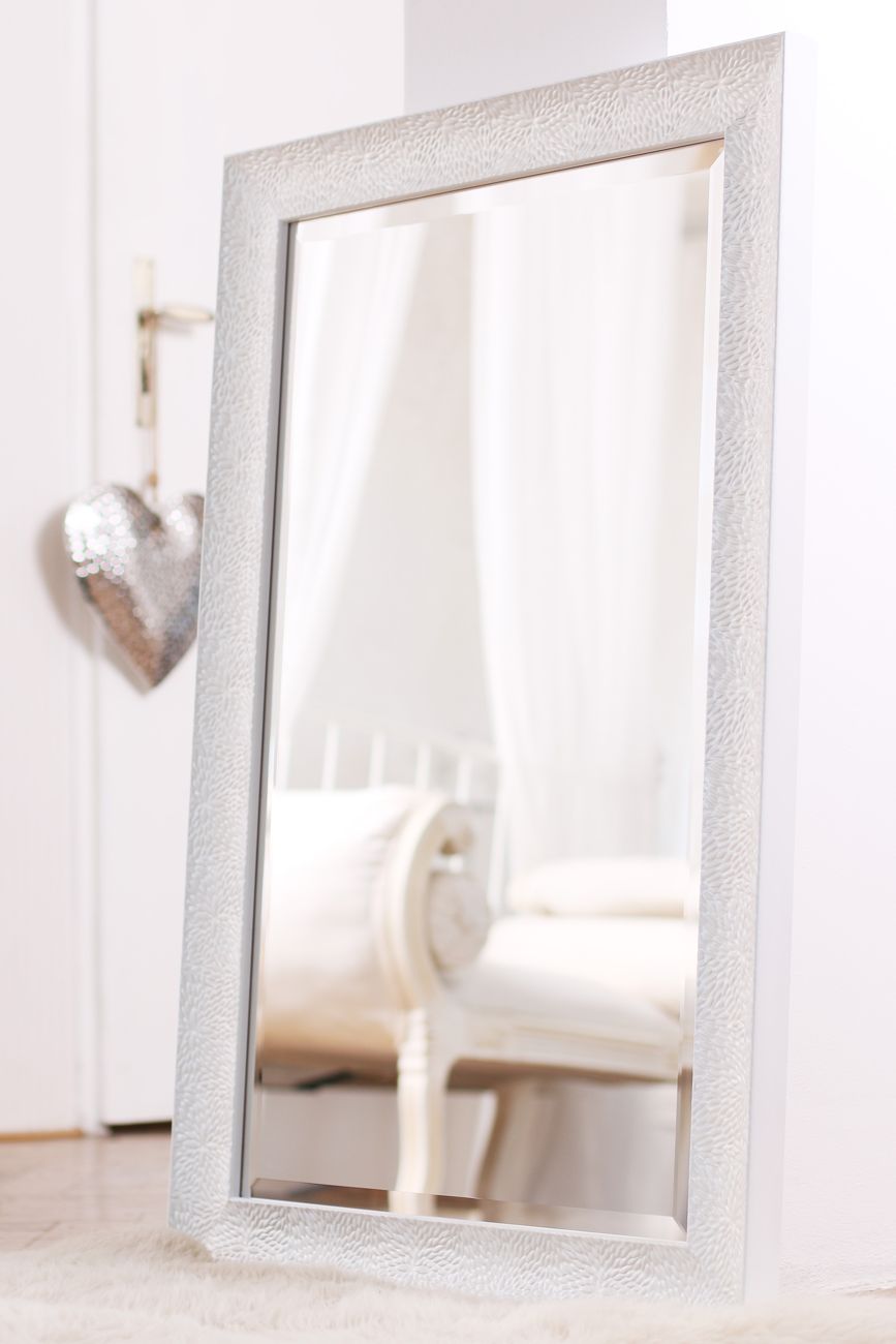 Krásné zrcadlo s broušenou fazetou v moderním bílém rámu stojící volně v prostoru bytu v Praze 7 | © Rámařství Frameit.cz