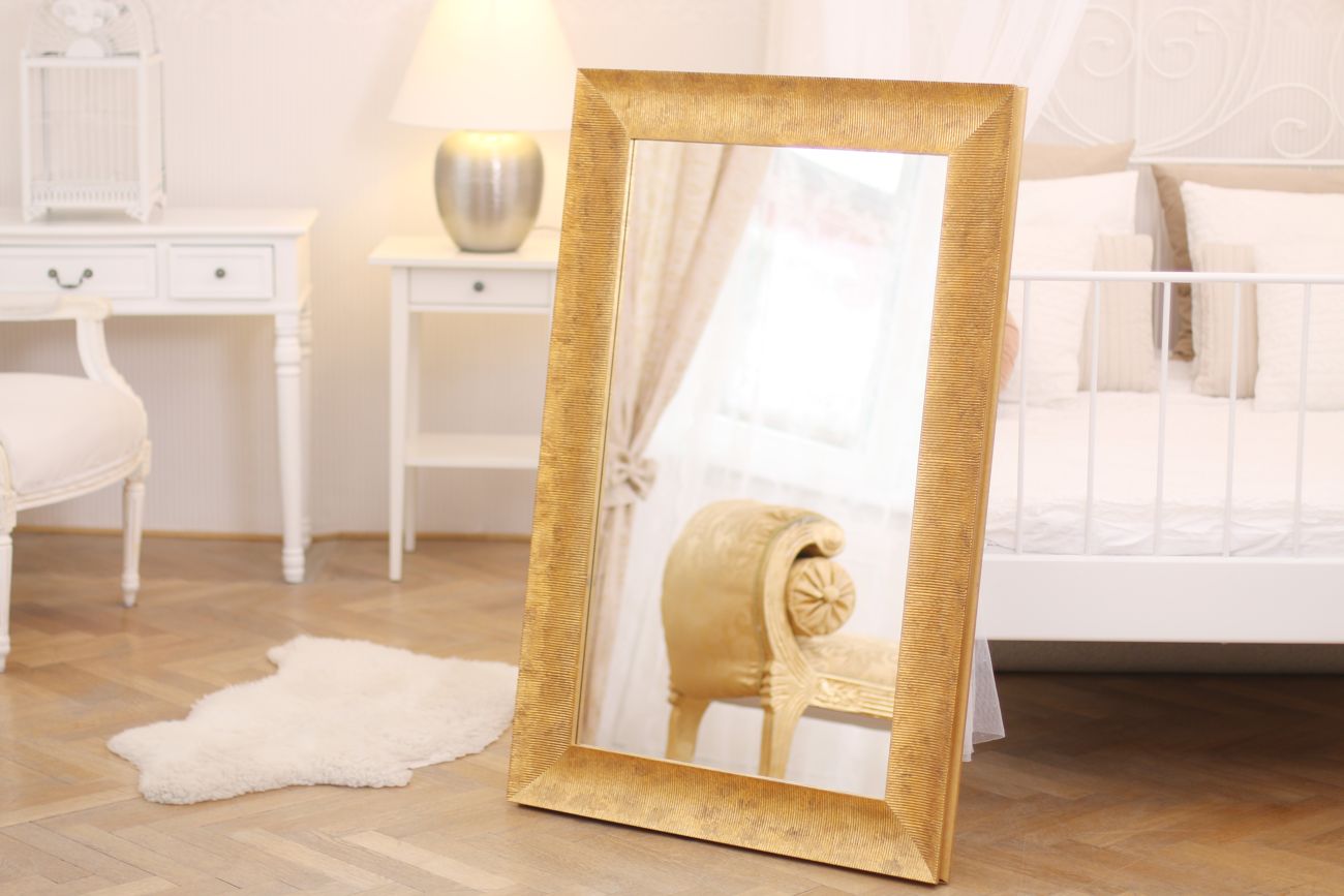Moderní zrcadlo v krásném zlaceném rámu s příčným pruhováním a patinou v interiéru ložnice | © Frameit