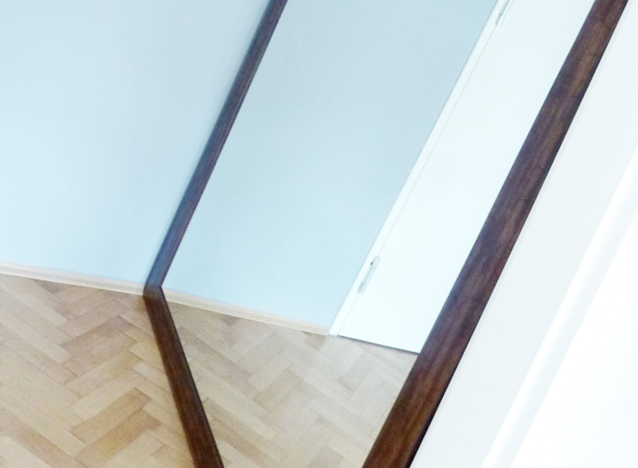 Velké XXL zrcadlo v dřevěném rámu opřené o zeď v interiéru moderní kanceláře | © Frameit
